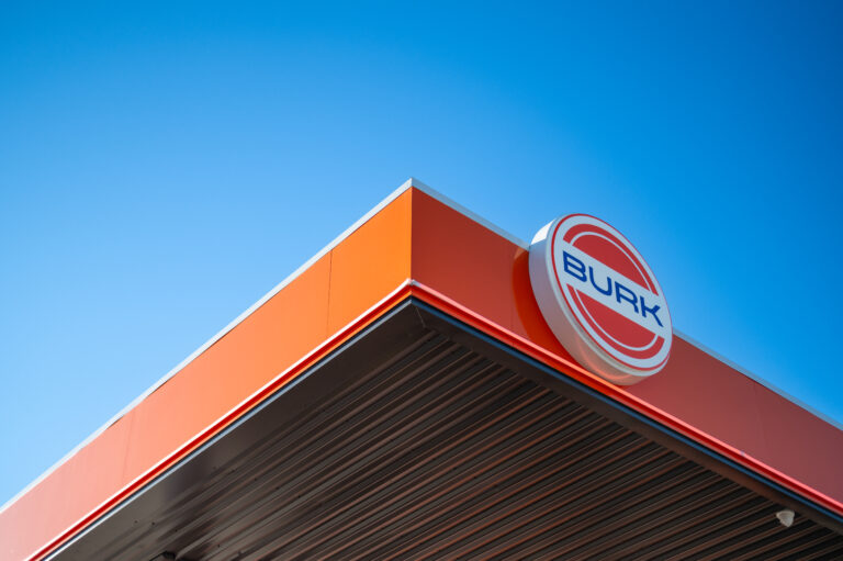 Burk Fuel station canopy with logo against clear blue sky, highlighting brand identity.