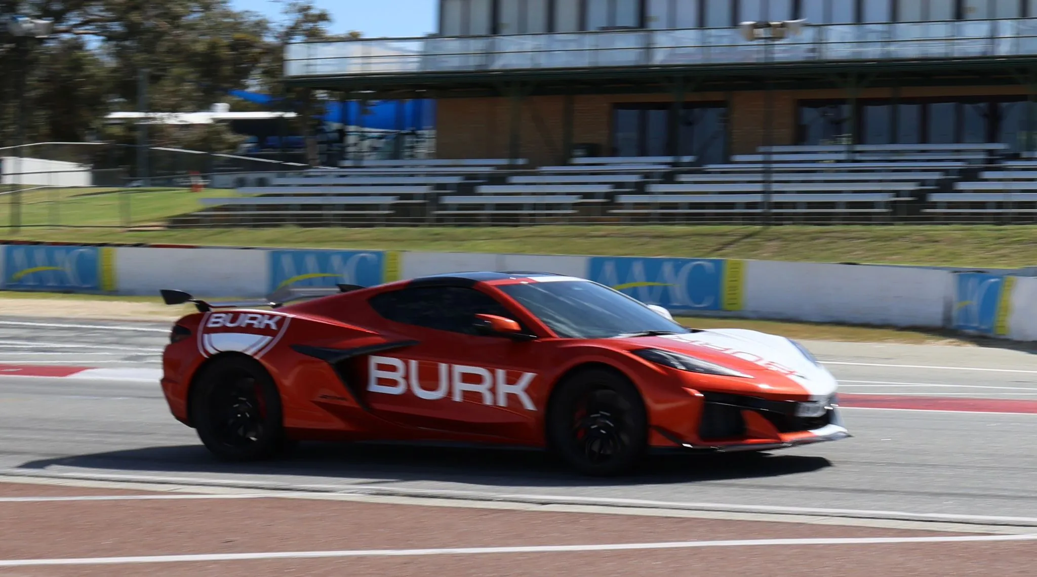 Burk fuel tanker with bold branding as a uniformed staff member stands beside it at a fuel station under bright daylight.